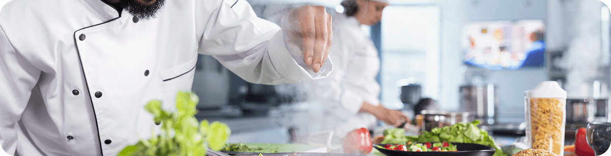 Chef adding fresh herbs to a dish in the kitchen